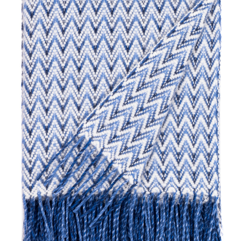 Blue wool throw blanket with wave-pattern texture and fringed edges, woven from soft New Zealand lambswool.